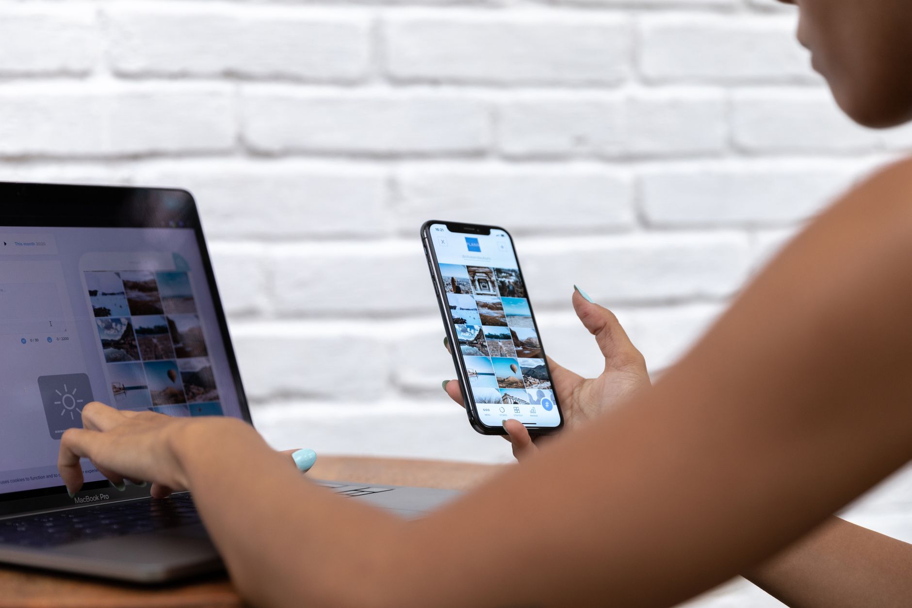 A person comparing social media posts on a smartphone and laptop screen while testing a workflow